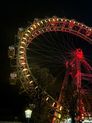 The Wiener Riesenrad, Illuminated giant Ferris Wheel glowing at night against dark sky at Prater...