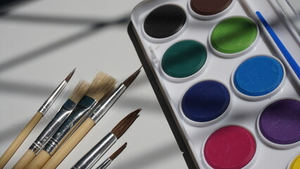 Paint brushes and watercolor paints on a white background, close-up