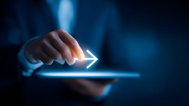Businessperson's hand interacts with glowing digital forward arrow emerging from a modern electronic device - Powered by Adobe