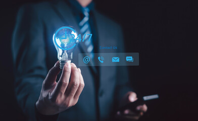 Businessman holding light bulb with 24 contact icons, representing customer support, online...