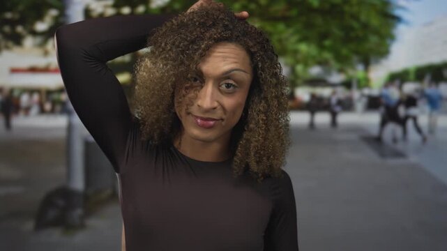 Trans woman wearing black top makes rock horns gesture on head in a crowded downtown street; rock fun.