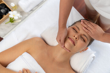 Panorama top view of woman enjoying relaxing anti-stress head massage and pampering facial beauty skin recreation leisure in dayspa modern light ambient at luxury resort or hotel spa salon. Quiescent