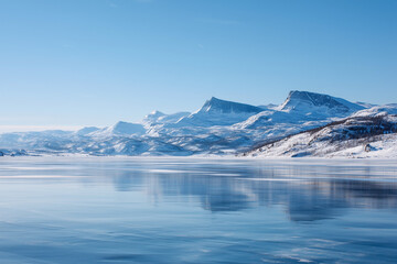 Obraz premium Frozen lake with perfect ice surface, distant snow-covered mountains, clear blue winter sky, majestic 