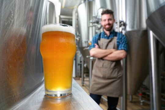 Craft beer served in a glass with a smiling brewer in the background