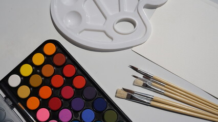 Watercolor paints and brushes on a white background, close-up