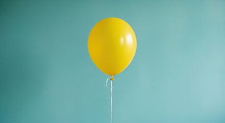 Bright yellow balloon floating against a blue wall