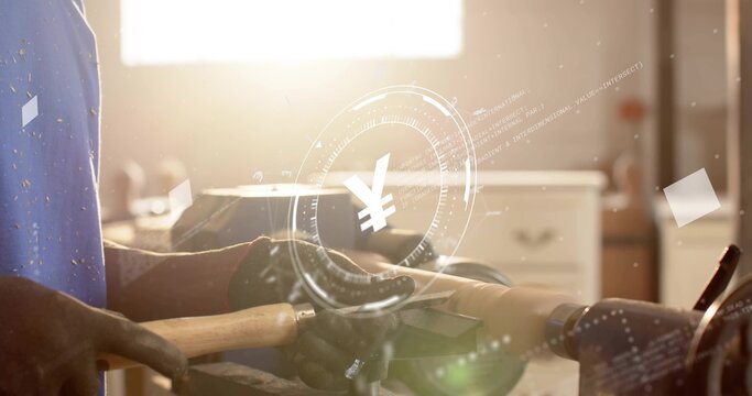 Gloved woodworker in blue tee tapping chisel against spinning spindle in workshop, with yen overlay
