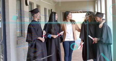 Celebrating mentor and graduates wearing black gowns on campus walkway, holding red ribbon diplomas