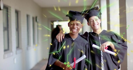 Smiling graduates wearing black mortarboards and gowns in corridor, holding red ribboned diplomas
