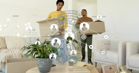 Couple carrying moving boxes inside living room, coffee table with plant and cup, network overlay