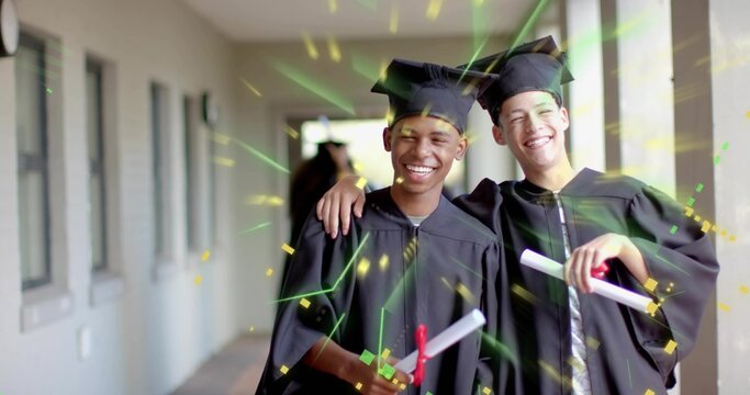 Smiling graduates wearing black mortarboards and gowns in corridor, holding red ribboned diplomas