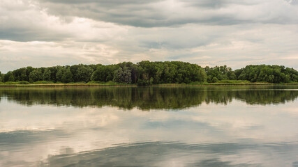 Calm Lake with Forest Reflection under Cloudy Sky