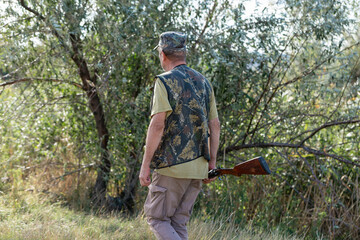 A hunter with a gun in camouflage clothing. A gentleman with a gun, medium shot, unrecognizable.