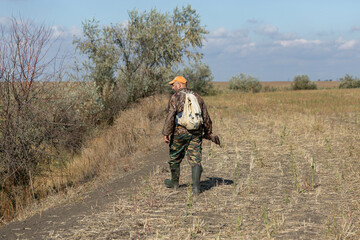 A hunter with a gun in camouflage clothing. A gentleman with a gun, medium shot, unrecognizable.