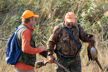A hunters holds a pheasant in his hands. A successful hunt, a trophy game.