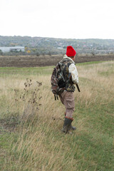 A hunter with a gun in camouflage clothing. A gentleman with a gun, medium shot, unrecognizable.