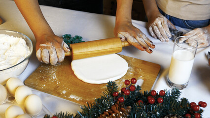 Mother and child are rolling out dough to bake Christmas cookies