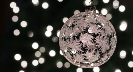Christmas ornament with intricate design hanging against a blurred backdrop of lights