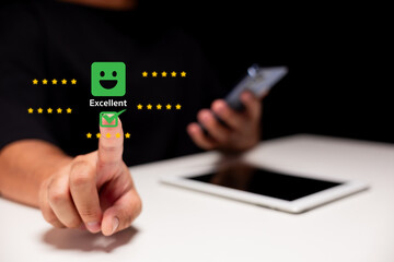 A hand with a finger pointing at a green 'Excellent' icon, symbolizing positive feedback or rating, with a smartphone in the background.