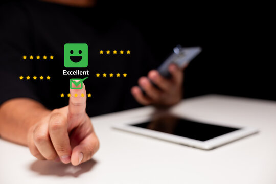 A hand with a finger pointing at a green 'Excellent' icon, symbolizing positive feedback or rating, with a smartphone in the background.