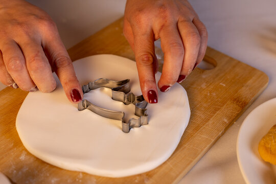  Woman is using a cookie cutter to prepare Christmas cookies
