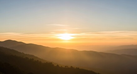 Obraz premium A serene sunrise cresting over a hazy mountain range, casting warm golden light and sunbeams across the tranquil valley
