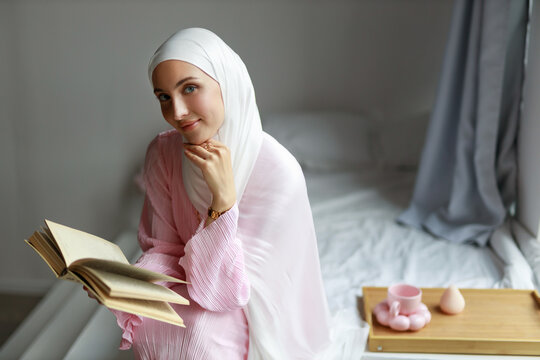 A beautiful young Muslim woman reading the Quran	
