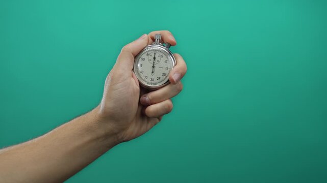 Man holding stopwatch against green background isolated signifying time measurement and precision concept.