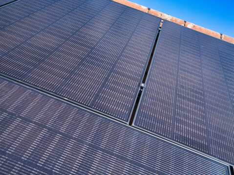 Close-up of photovoltaic panels on a house roof against a bright blue sky in the United Kingdom, symbolizing clean power and modern home efficiency.
