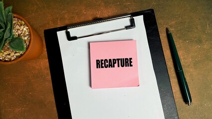 RECAPTURE writing concept on isolated sticky notes on work desk.