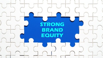 Strong Brand Equity writing concept in the middle of the puzzle. Blue background.