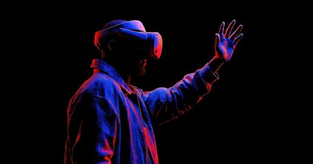 Man wearing virtual reality headset interacts with digital space in dark setting.