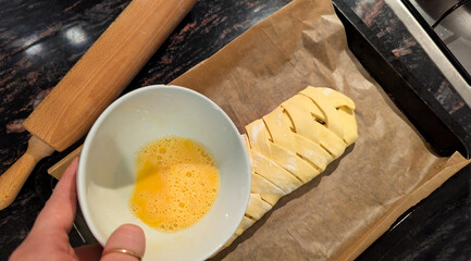 Homemade apple strudel preparation with egg wash and puff pastry braid