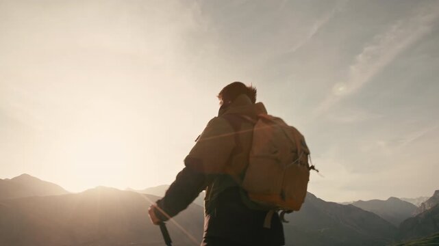 Traveler standing on mountain peak at sunrise raising arms to glowing sky camera moving from sun to silhouette concept of victory freedom gratitude awakening and harmony with nature