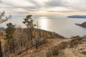 Hillside forest, a rocky path, and calm water reflecting the sunset. nature, travel, and autumn colors and scenic overlooks. Baikal Lake in Siberia, Russia.