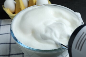 Whisking egg whites with hand mixer at table, closeup
