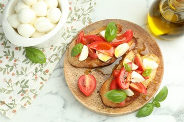Tasty bruschettas with mozzarella cheese, tomatoes and basil on white marble table, flat lay