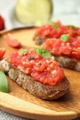 Tasty bruschettas with tomatoes and basil on table, closeup