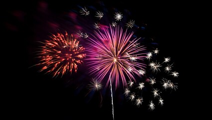 A spectacular display of vibrant pink, red, and white fireworks exploding beautifully against the dark night sky during a festive occasion