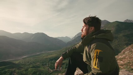 Bearded man traveler sitting on mountain edge in morning light camera moving around concept of inner peace mindfulness sunrise freedom self discovery nature connection spiritual awakening - Powered by Adobe