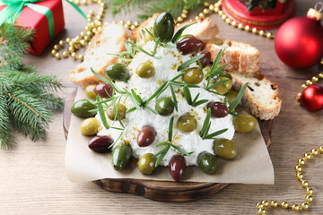 Delicious Christmas tree cheese ball with olives, rosemary, bread and decor on wooden table, closeup. New Year's appetizer