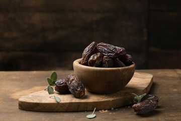 Dates in wooden bowl on rustic table, natural sweet dried fruit, healthy organic snack
