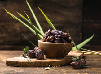 Dates in wooden bowl on rustic table, natural sweet dried fruit, healthy organic snack