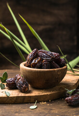 Dates in wooden bowl on rustic table, natural sweet dried fruit, healthy organic snack