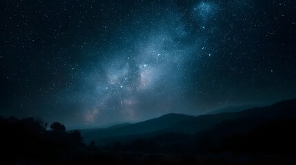 Fototapeta premium A vast expanse of the Milky Way galaxy stretches across a starry night sky above dark silhouetted mountains