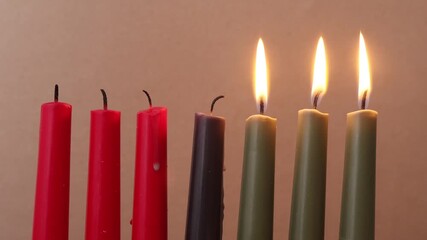 African American Kwanzaa holiday concept with traditional lit candles. Seven candles red, black and green - Powered by Adobe