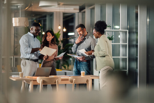 Diverse business colleagues collaborating on project late at night