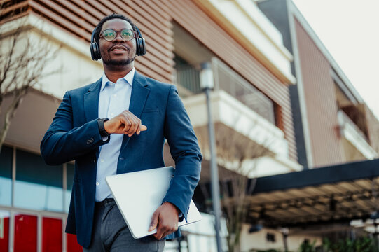African american businessman walking city, checking smartwatch - Powered by Adobe