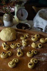 Process of making traditional Swedish saffron buns. S-shaped yeast buns spiced with saffron and decorated with raisins on wooden board.