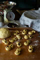Process of making traditional Swedish saffron buns. S-shaped yeast buns spiced with saffron and decorated with raisins on wooden board.